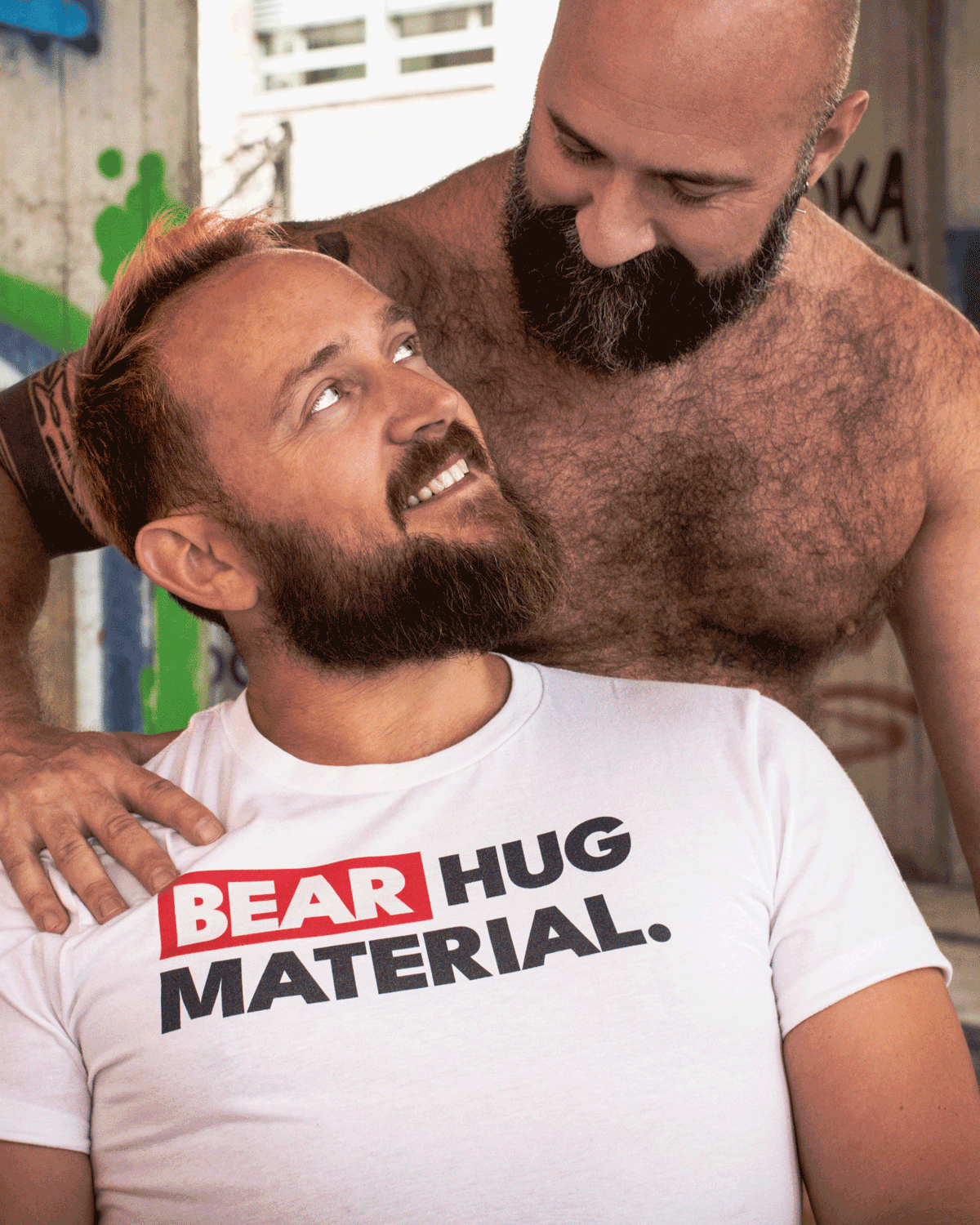Scruffy Cub Bear Hug Material white graphic T-shirt for men, modelled by a bearded man with another bear