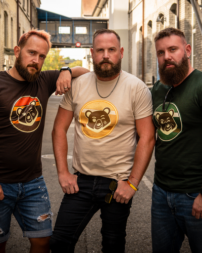 Three bearded men wearing Scruffy Cub Horizon T-shirts in sunset brown, desert beige and forest green