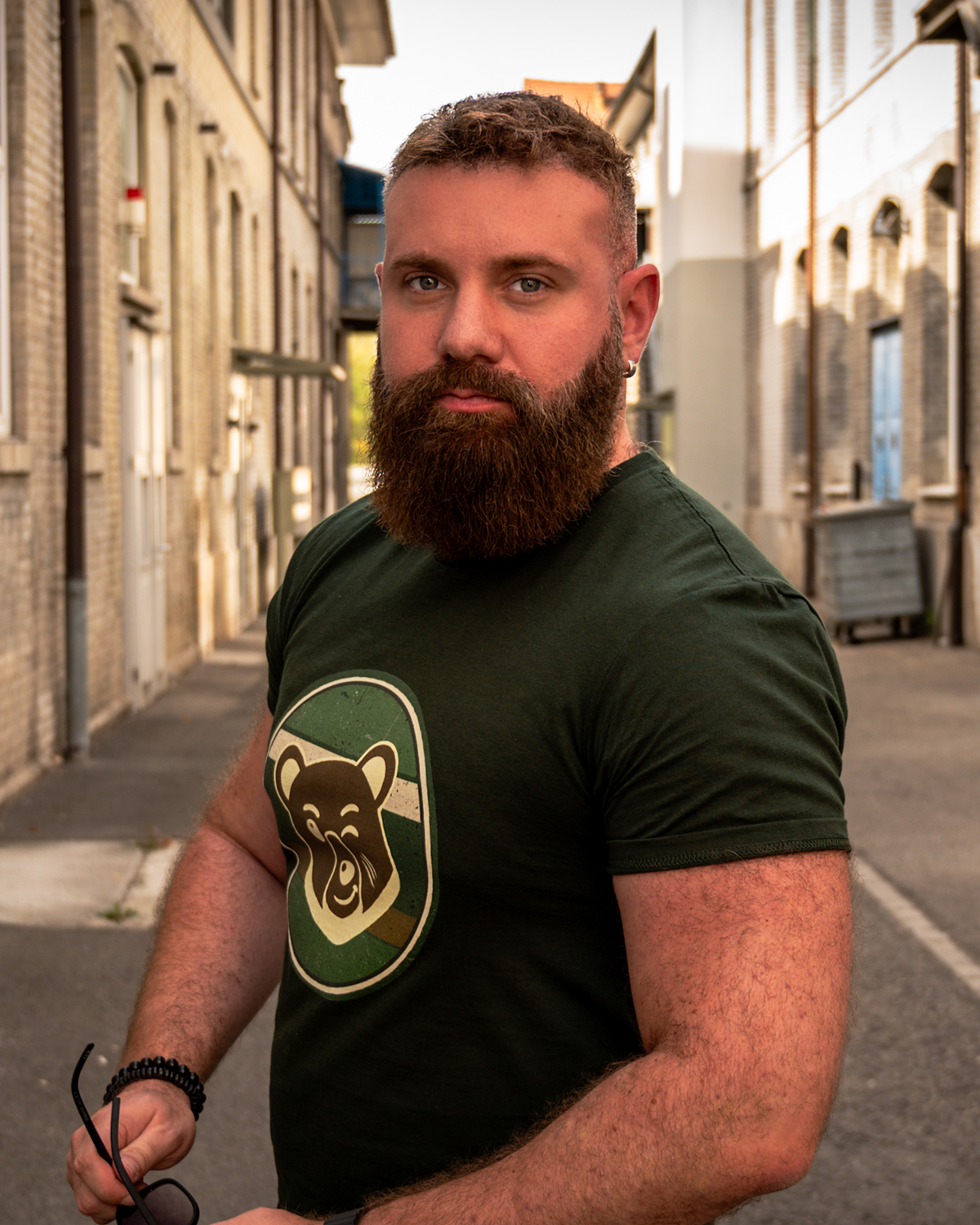 Bearded man wearing the desert beige Scruffy Cub Horizon T-shirt with a retro bear graphic